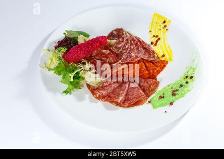 Gerichte aus verschiedenen Wurstsorten mit Kräutern, Gewürzen und Soße auf einem weißen Teller auf hellem Hintergrund Stockfoto