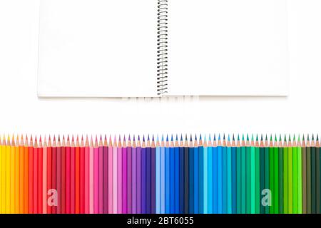 Bunte Buntstifte zum Zeichnen von Bildern und Skizzen. Auf weißem und gelbem Hintergrund. Draufsicht Stockfoto