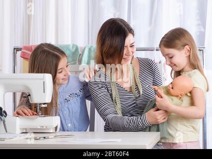 Meister Lehrer zeigt Mädchen, wie man Kleider für Puppe zu machen Stockfoto