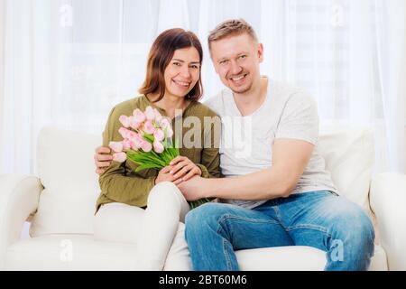 Glücklich schönes Paar auf der Couch mit Überraschung Bouquet sitzen Stockfoto