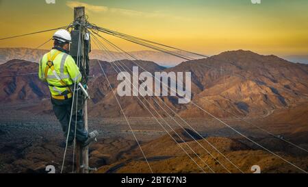 Lineman (oder Linarbeiter oder Techniker) in einer Remote Desert Landschaft, die eine Telefonleitung repariert Stockfoto