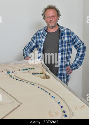 23. Mai 2020, Brandenburg, Altranft: Reinier Scheers, Tischler und Designer des Modells, steht an seiner Marmorbahn im Oderbruch Museum Altranft. Reinier Scheers Aufgabe war es, das Strömungssystem des Oderbruchs mit Glasmurmeln sinnlich erlebbar zu machen. Das Ergebnis ist eine einzigartige Marmorbahn einer Region in Ostbrandenburg. Die Marmorbahn wird nicht mit elektrischer Energie betrieben. Nur Mechanik und Schwerkraft treiben dieses neue Highlight des Museums an. Und wer das Museum kennt, weiß, dass hier alles berührt werden kann oder sollte: Lernen durch Spielen, Lernen durch Berührung ist das Programm dort. Th Stockfoto