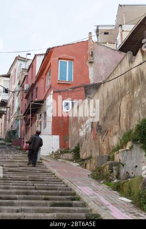 Izmir, Türkei - 7. Februar 2015: Ein Mann geht die Straße hinauf in der Nähe von bunten Wohnhäusern. Straßenansicht des alten Izmir, Türkei Stockfoto