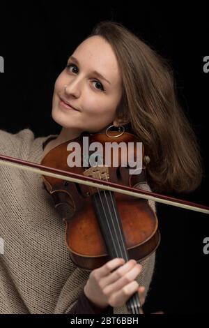 Attraktive lächelnde Frau Geigerin widmen ihre antike Barockvioline während einer Live-Performance oder Konzert über einem dunklen Hintergrund in der Nähe Stockfoto