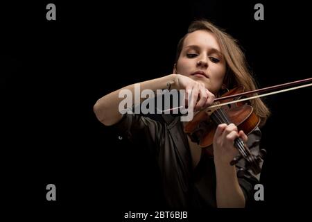 Leidenschaftliche professionelle Musikerin spielt auf einer klassischen antiken handgefertigten Holzbarocke Geige mit Fokus auf ihre Hand und Bogen über schwarz Stockfoto