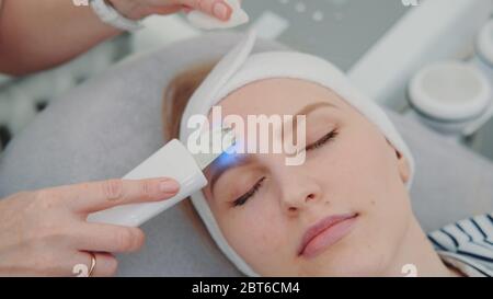 Nahaufnahme von Kosmetikerin, die Kavitation beim Peeling der Gesichtshaut macht. Frau, die nach einer arbeitsharten Woche ausruht. Stockfoto