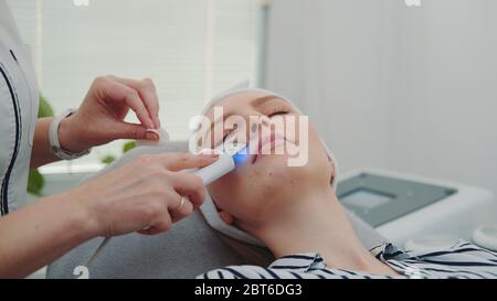 Nahaufnahme von professionellen Kosmetikerin, die Kavitationspeeling auf Gesicht der jungen Frau im Schönheitssalon mit moderner Ausstattung und angenehmer Atmosphäre macht. Stockfoto