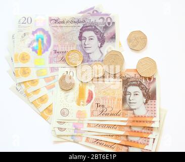 Zehn 10 und 20 britische Pfund-Banknoten und Münzen auf weißem Hintergrund Stockfoto