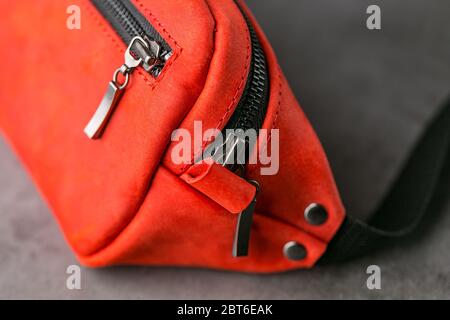 Rote Hüfttasche aus Leder, Banane auf grauem Hintergrund. Handgefertigt Stockfoto