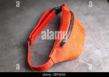 Rote Hüfttasche aus Leder, Banane auf grauem Hintergrund. Handgefertigt Stockfoto