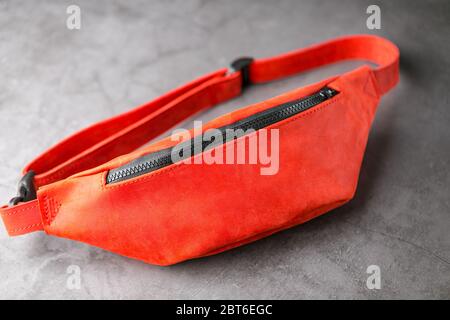 Rote Hüfttasche aus Leder, Banane auf grauem Hintergrund. Handgefertigt Stockfoto