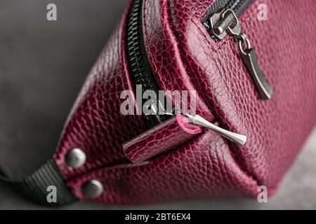 Taillentasche aus dunkelrotem Leder, Banane auf grauem Hintergrund. Handgefertigt Stockfoto