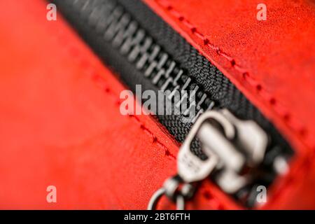 Reißverschluss-Slider für eine Tasche aus strukturiertem rotem Leder. Handgefertigt. Nahaufnahme Stockfoto