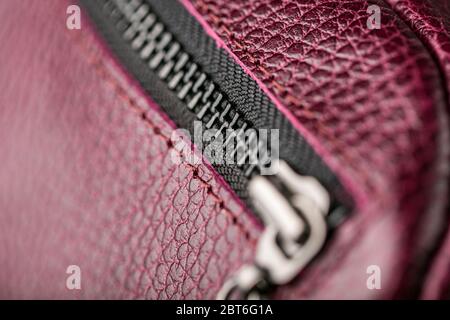 Reißverschluss-Slider für eine Tasche aus strukturiertem rotem Leder. Handgefertigt. Nahaufnahme Stockfoto