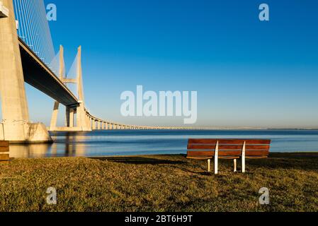 Sonnenuntergang mit Blick auf die Brücke mit einer Bank im Vordergrund. Stockfoto