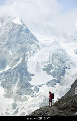 Unglaublich schöne Mount in Schweizer Alpen - Ober Gabelhorn, männlicher Wanderer mit Rucksack auf einem Hang stehend genießen eine kalte ruhige Landschaft. Konzept der Freiheit, Bergwandern, Tourismus und Alpinismus Stockfoto