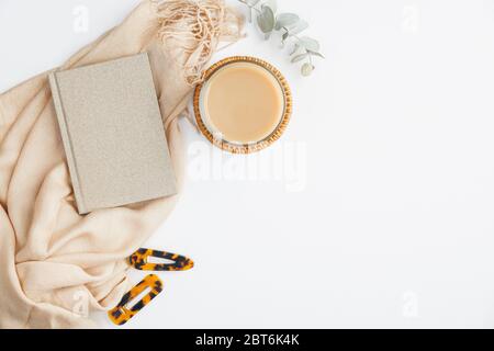 Moderner Schreibtisch für das Home Office mit Notizbuch aus Papier, beigefarbener Decke, Tasse Kaffee auf weißem Hintergrund. Flach, Ansicht von oben modischer, femininer Arbeitsplatz. Stockfoto