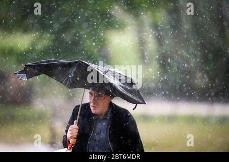 Ein Mann geht am ersten Tag des Feiertagswochenendes durch einen starken Regenschauer im St James's Park im Zentrum Londons, während Menschen in Parks und Strände strömen, während die Lockdown-Maßnahmen gelockert wurden. Stockfoto