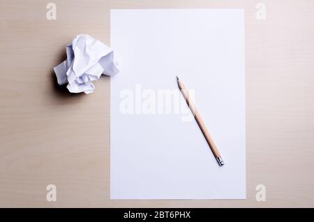 Nahaufnahme eines leeren weißen Buchstabens und einer zerknitterten Papierkugel mit Bleistift auf Holztisch oder Tisch, Büro- oder Schreibkonzept, flaches Lay, direkt darüber Stockfoto