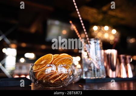 Getrocknete Orangen liegen in einer Glasvase, Früchte werden in Scheiben geschnitten ​​in Kreise, schönes Licht, close-up, ein Glas im Hintergrund, Blendung und Lichter in der Stockfoto