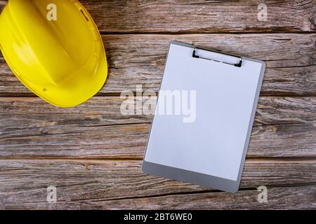 Architekt Bauherren Wartung Bürobau, gelbe Hut mit Verwendung von Tapeten Notizblock auf Holz Tisch Hintergrund. Stockfoto