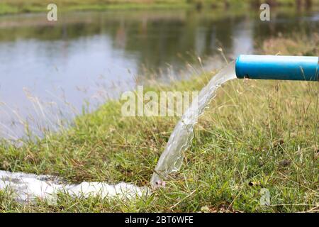 Das Wasser, das aus dem Rohr in die natürliche Wasserquelle fließt. Das Wasser, das aus dem Rohr in die natürliche Wasserquelle fließt. Stockfoto