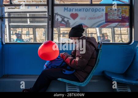 Russischer Junge hält einen roten Ballon in der Hand und Er transportiert mit der Straßenbahn nach Magnitogorsk Stockfoto