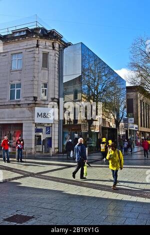 Shopper genießen die Wintersonne, während sie am Marks & Spencer Store in Cardiff's Queen Street vorbeischlendern. Stockfoto