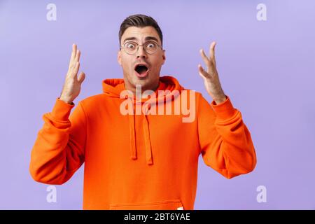 Foto von schockierten schreienden jungen Mann isoliert über lila Hintergrund trägt Brillen. Stockfoto