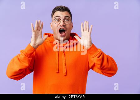 Bild von schockierten emotionalen jungen Mann isoliert über lila Hintergrund trägt Brillen. Stockfoto