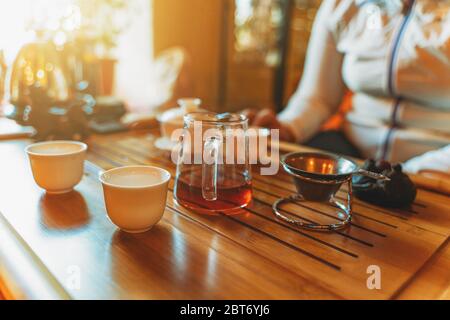 Chinesische Tee-Zeremonie auf hölzernen Tee-Tisch im Sonnenlicht, selektiver Fokus. Stockfoto