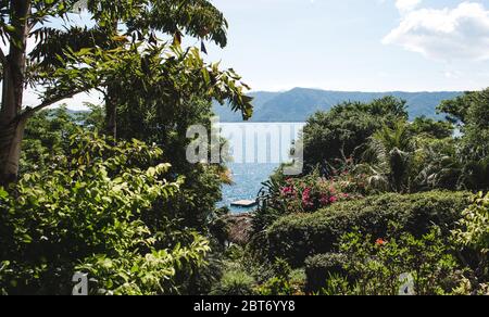 Schwimmende Plattform für Entspannung auf dem Kratersee der Laguna de Apoyo, Nicaragua, durch Bäume gesehen Stockfoto