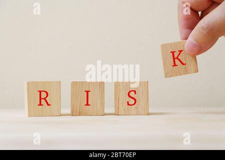 Das Wort 'Risiko' auf dem Holzwürfel mit der Hand, die den Buchstaben K. Stockfoto