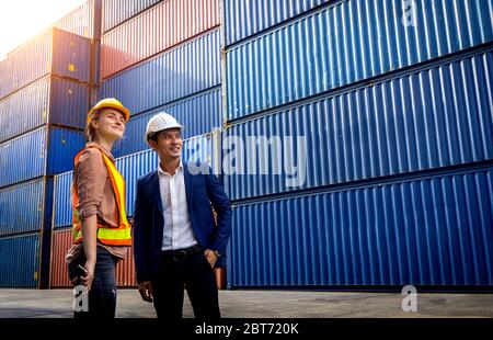 Zwei Vorarbeiter, eine Frau und ein Mann, stehen zusammen und blicken auf den Hintergrund des Frachtcontainers. Stockfoto