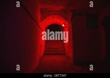 Treppe mit Stufen im Tunnel des unterirdischen Militärbunkers mit rotem Licht. Stockfoto