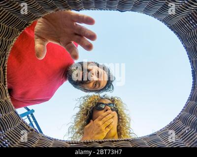 Erwachsene kaukasischen Paar Blick in einen Eimer und tun überrascht Ausdruck - Innen innen Weitblick - Überraschung Konzept mit blauen Himmel im Hintergrund und m Stockfoto