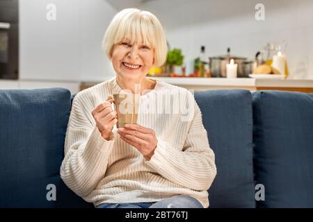 Ruhestand. Ältere Frau zu Hause sitzen trinken heißen Tee lachen fröhlich genießen Abend Stockfoto