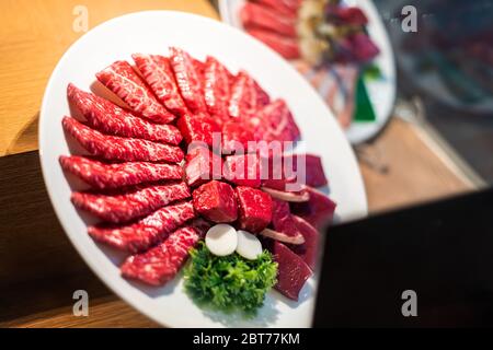 Nahaufnahme der Teller-Ausstellung außerhalb des Restaurants mit roten rohen Fleisch kobe oder wagyu Rindfleisch hinter Glasfenster in Tokio Stockfoto