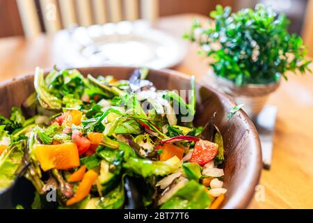 Nahaufnahme von frischen grünen Salat gemischt Salat Salat in Schüssel Teller mit Paprika in rustikalen Speisesaal Holztisch und Tageslicht Stockfoto