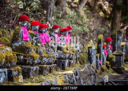 Berühmte Stein-Iser-Statuen Reihen sich in Kanmangafuchi Abyss, Nikko, Tochigi in Japan mit roten Hüten und rosa Lätzchen, die die Toten schützen Stockfoto