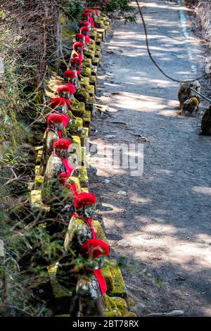 Hoher Winkel über Ansicht des Steinfelsen Iser Statuen Reihe in Kanmangafuchi Abyss, Nikko, Tochigi in Japan mit roten Hüten und Lätzchen Schutz der Toten Stockfoto