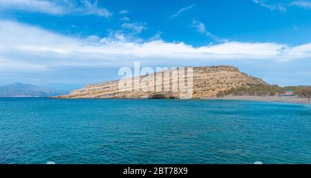 Panorama von Matala, schöner Strand auf Kreta, Wellen und Felsen. Matala Dorf mit Höhlen und blauen Himmel. Matala, Kreta. Stockfoto