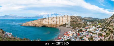 Panorama von Matala, schöner Strand auf Kreta, Wellen und Felsen. Matala Dorf mit Höhlen und blauen Himmel. Matala, Kreta. Stockfoto