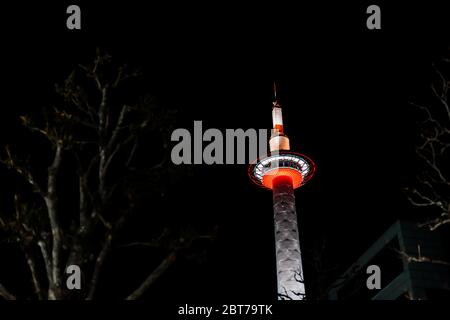 Kyoto, Japan Skyline Turm in der Nähe Bahnhof in der dunklen schwarzen Nacht und beleuchtete Gebäude rot Farbe am Abend Blick nach oben mit Baum Stockfoto