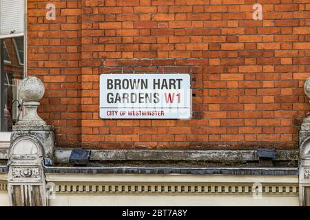 Das Straßenschild der Brown Hart Gardens hoch oben an einer roten Backsteinmauer in Mayfair, London W1 Stockfoto
