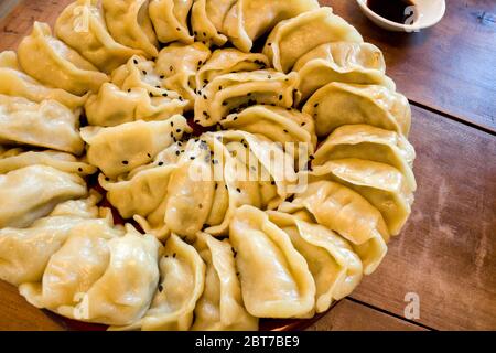 Handgemachte chinesische Knödel Jiaozi mit schwarzen Sesamsamen, die schön im Kreis für das chinesische Neujahr angeordnet sind Stockfoto