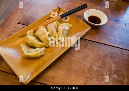 Handgemachte chinesische Knödel Jiaozi mit schwarzen Sesamsamen wunderschön auf einem Keramikplatte mit Koteletts und Sojasoße für das chinesische Neujahr angeordnet Stockfoto