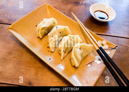 Handgemachte chinesische Knödel Jiaozi mit schwarzen Sesamsamen wunderschön auf einem Keramikplatte mit Koteletts und Sojasoße für das chinesische Neujahr angeordnet Stockfoto