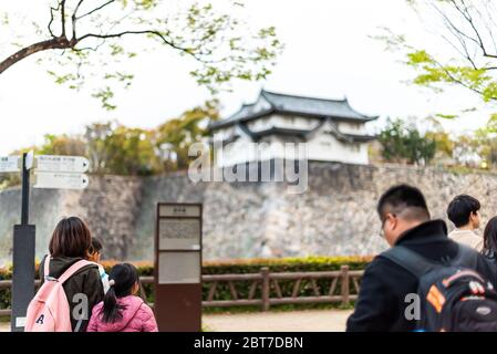 Osaka, Japan - 13. April 2019: Blick auf den Burggraben am Abend mit Menschen, die im Frühling mit Touristen und verschwommenem Hintergrund auf das Gebäude schauen Stockfoto