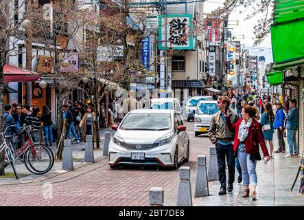 Nara, Japan - 14. April 2019: Menschen Touristen zu Fuß auf Bürgersteig Sanjo dori Straße in der Innenstadt in Richtung Park mit Geschäften und Kirsch BL Stockfoto